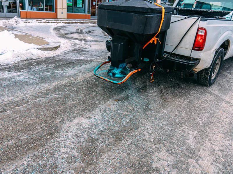 Truck spreading ice-melting salt throughout a slippery parking lot